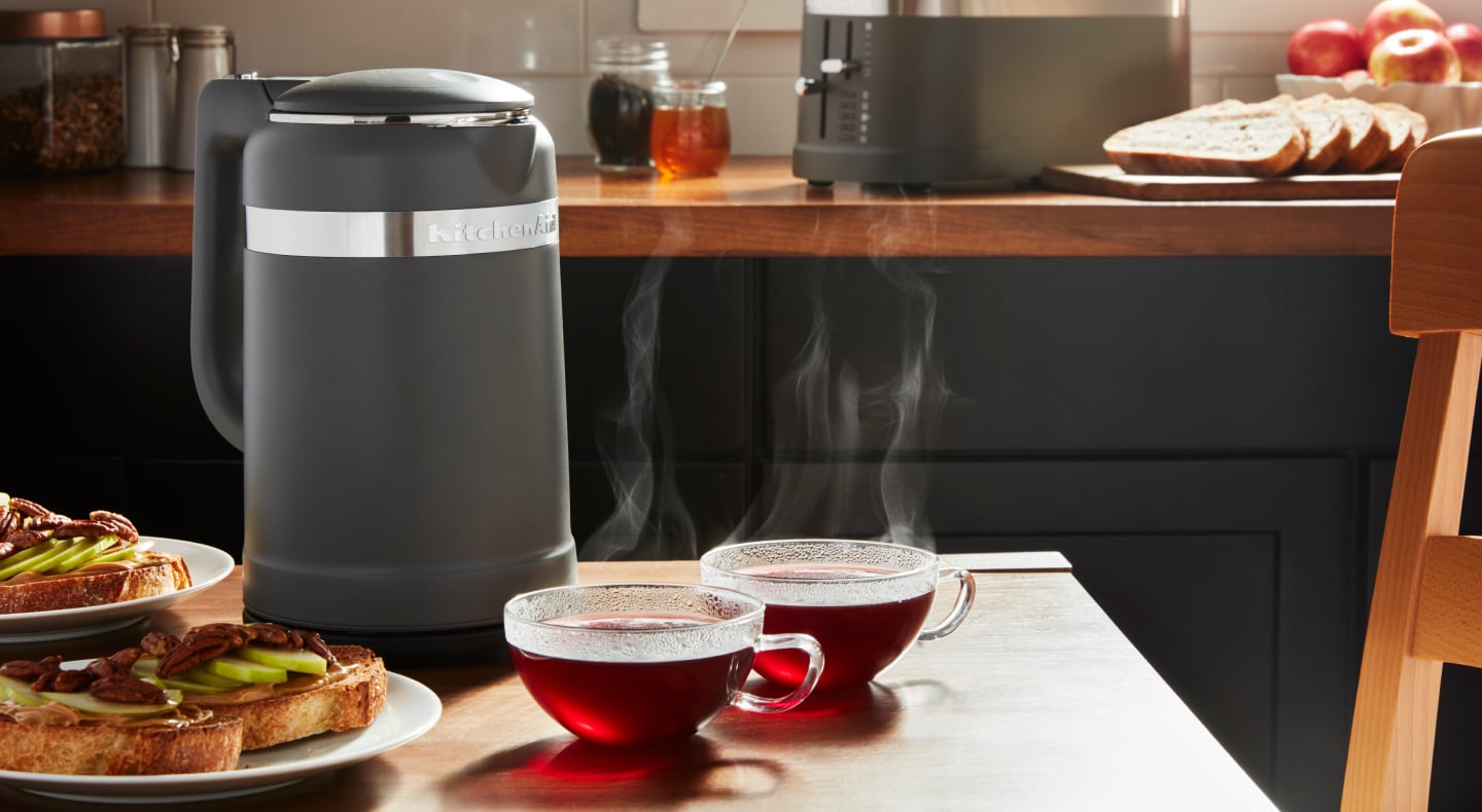 Black KitchenAid® electric kettle next to two glass mugs of tea Black KitchenAid® electric kettle next to two glass mugs of tea
