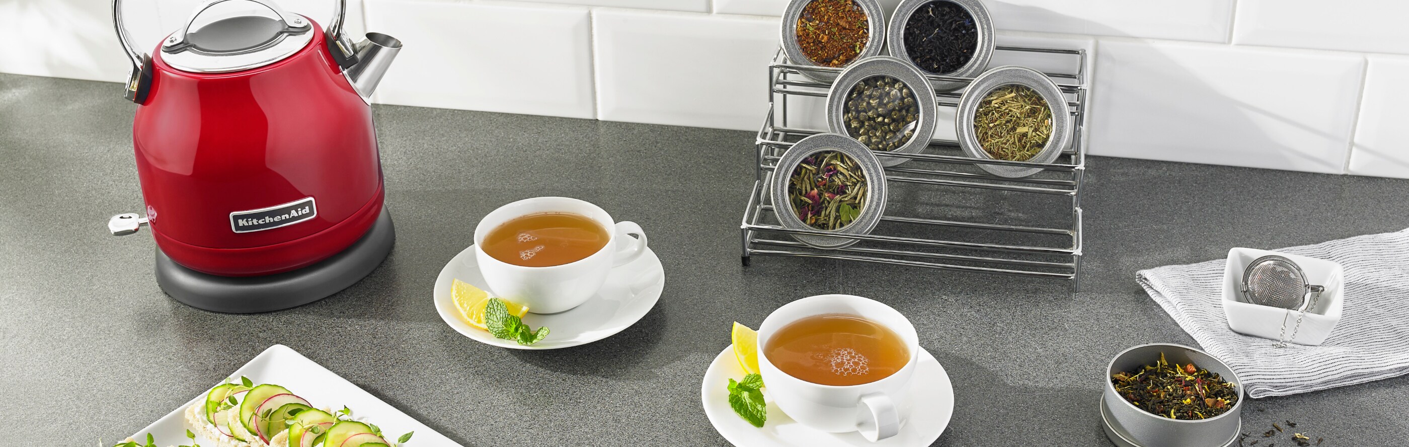 Red KitchenAid® electric kettle next to two cups of tea