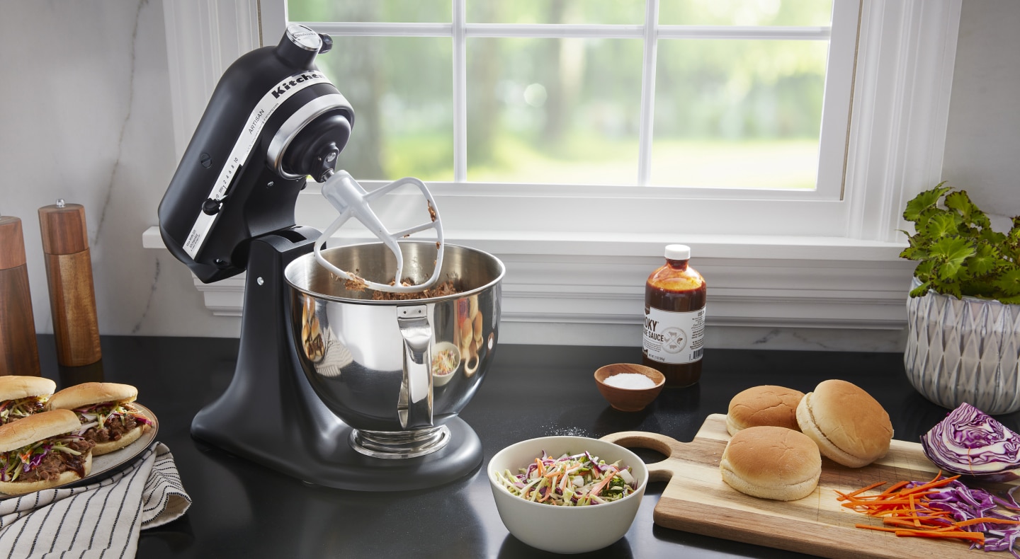 A black tilt-head KitchenAid® stand mixer mixing meat A black tilt-head KitchenAid® stand mixer mixing meat