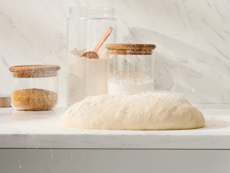 Dough on a countertop near a container of flour