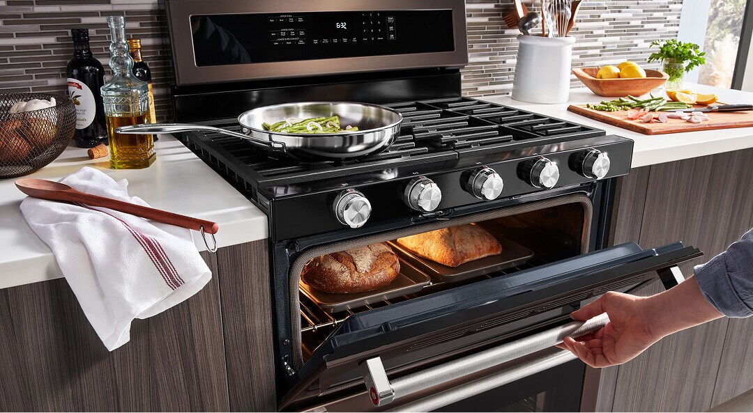 A person opening an oven with bread inside
