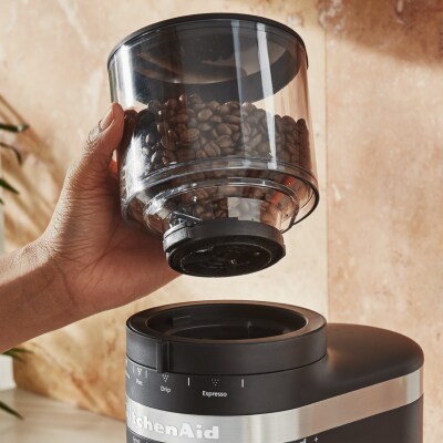 Hand removing a bean hopper from a burr grinder