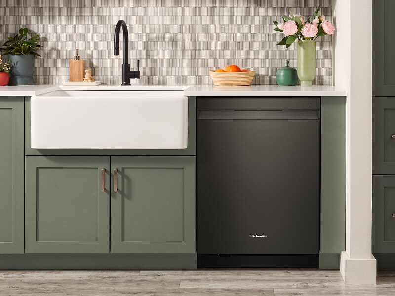 The interior of a kitchen with green cabinetry and a black faucet