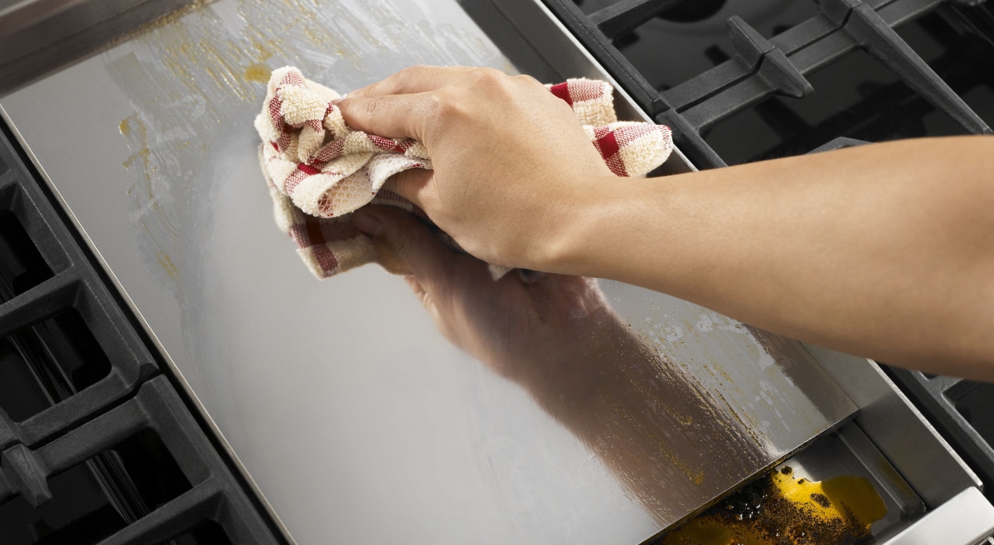 Person wiping griddle with clean dish rag Person wiping griddle with clean dish rag