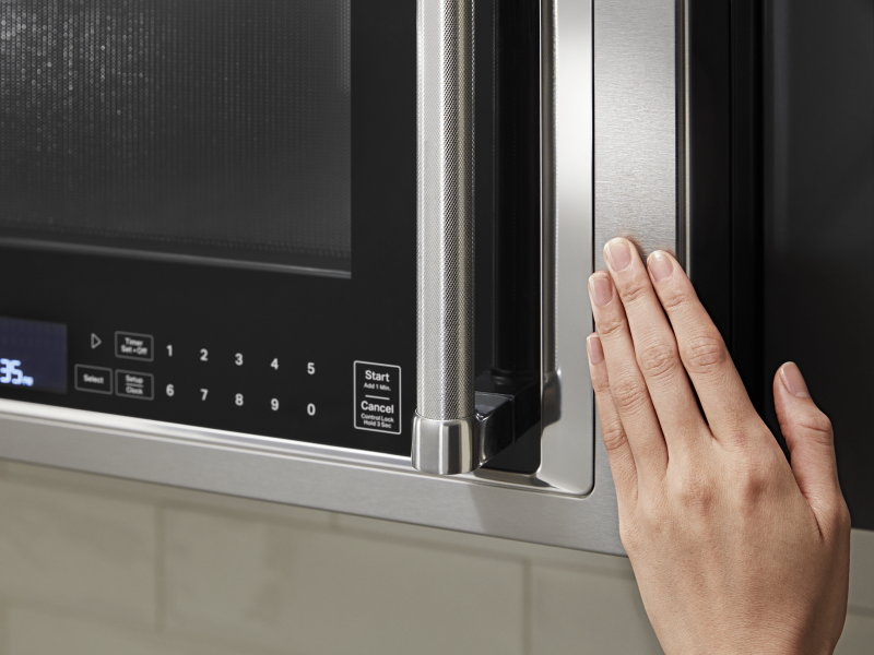 Hand closing a KitchenAid® over the range microwave Hand closing a KitchenAid® over the range microwave