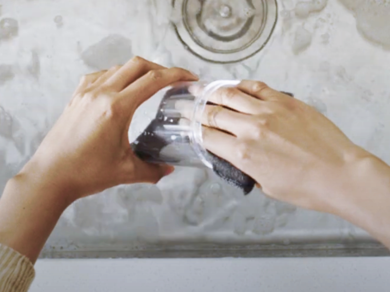 Person washing container with a sponge