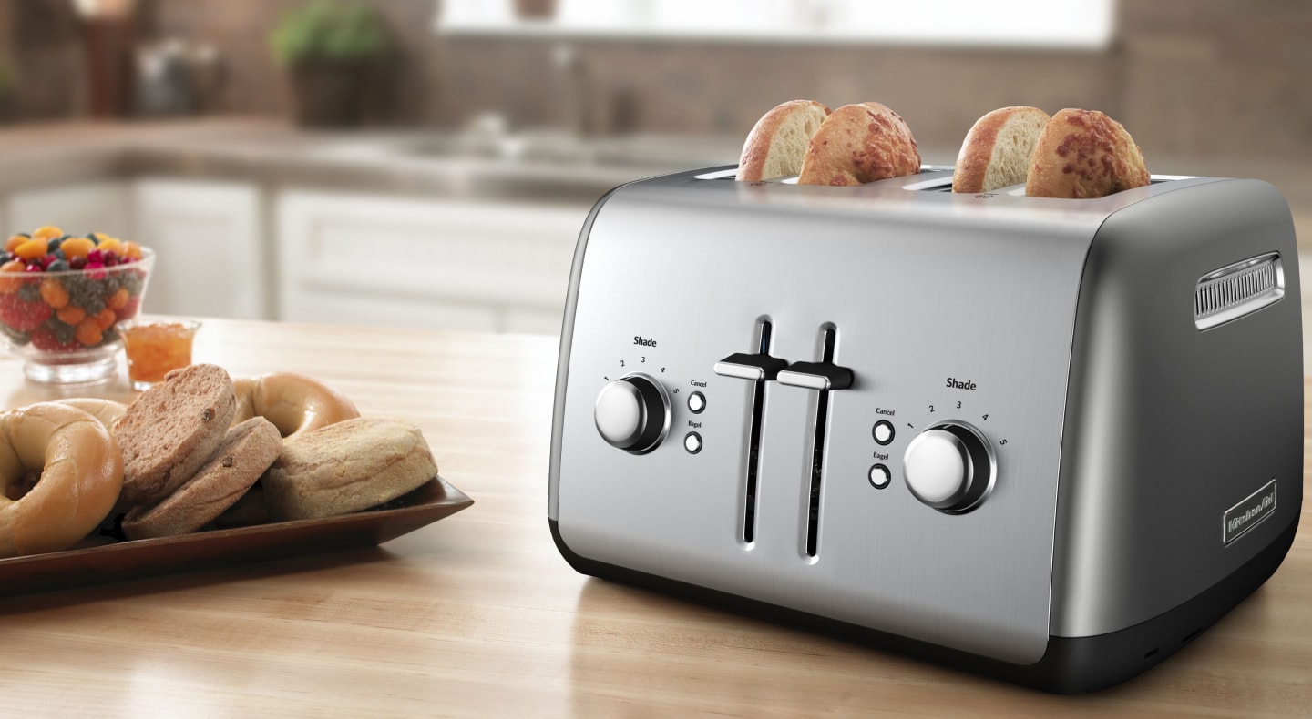 Bagel slices in a silver 4-slice KitchenAid® toaster on a modern kitchen counter. Bagel slices in a silver 4-slice KitchenAid® toaster on a modern kitchen counter.