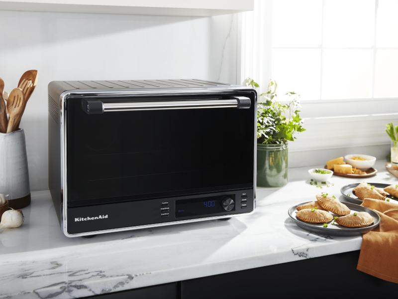 A black KitchenAid® air fryer and fresh empanadas on a countertop A black KitchenAid® air fryer and fresh empanadas on a countertop