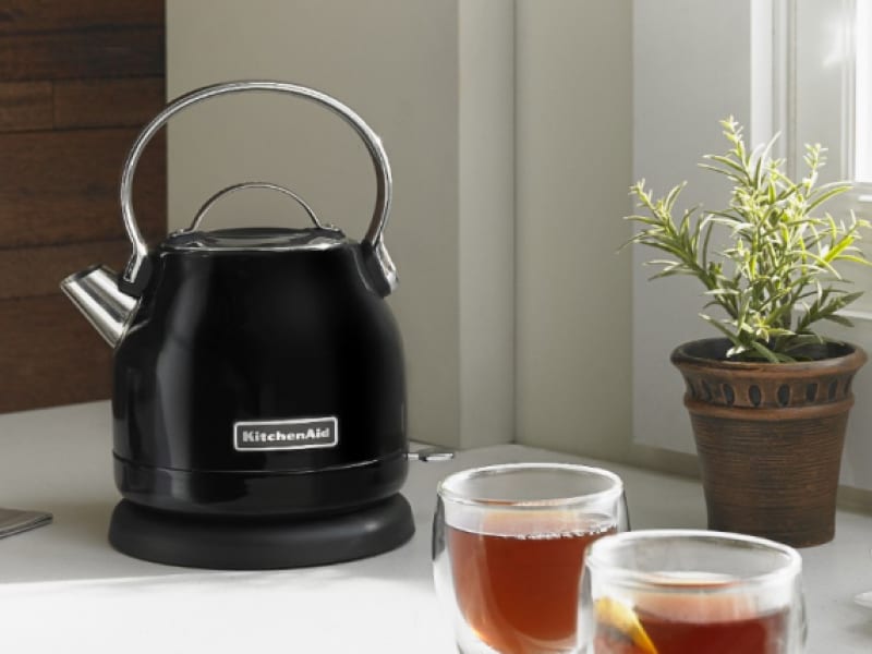 KitchenAid® electric kettle on a kitchen counter next to cups of fresh brewed tea KitchenAid® electric kettle on a kitchen counter next to cups of fresh brewed tea