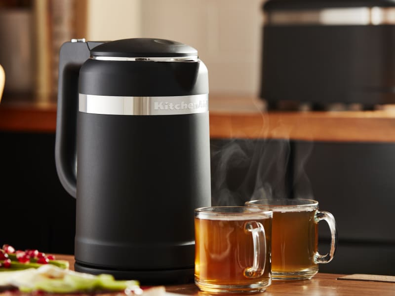 Black electric tea kettle on a countertop next to full glasses of tea Black electric tea kettle on a countertop next to full glasses of tea