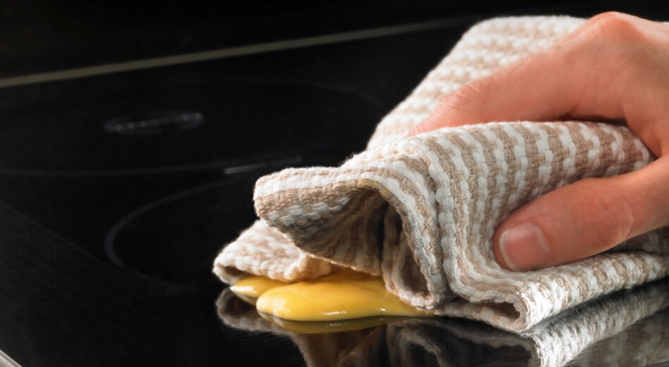 Hand wiping residue off of a cooktop Hand wiping residue off of a cooktop