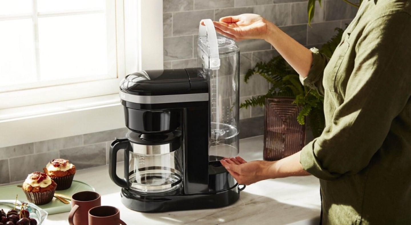 Woman replacing water tank in coffee machine Woman replacing water tank in coffee machine