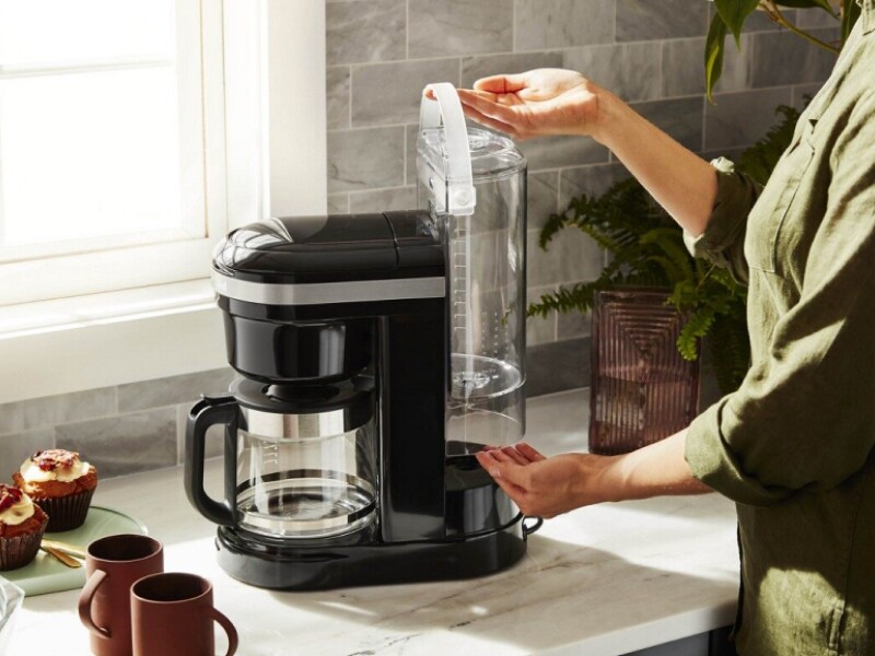 Woman replacing water tank in coffee machine Woman replacing water tank in coffee machine