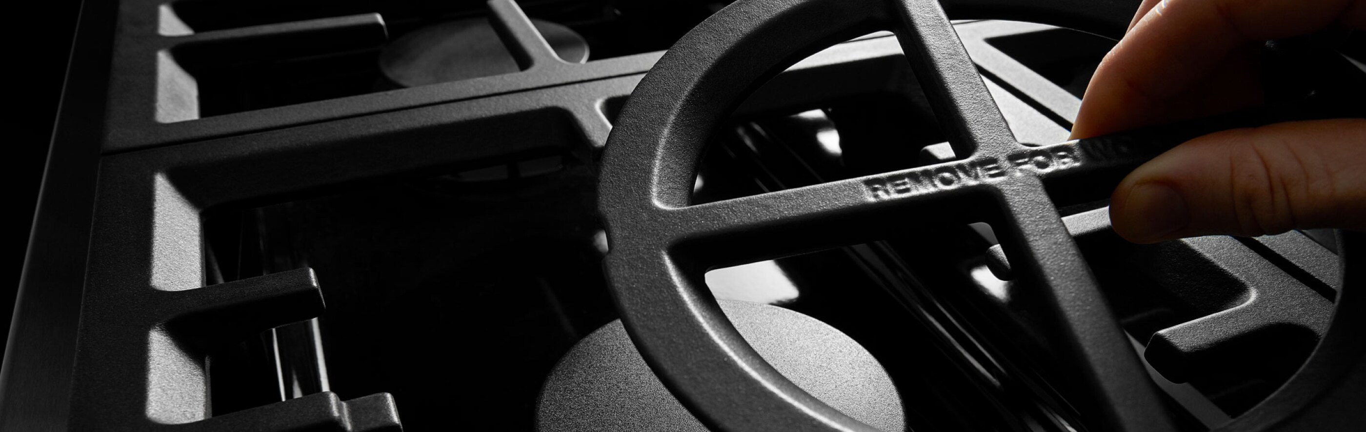 A black grate being removed from a stove top.