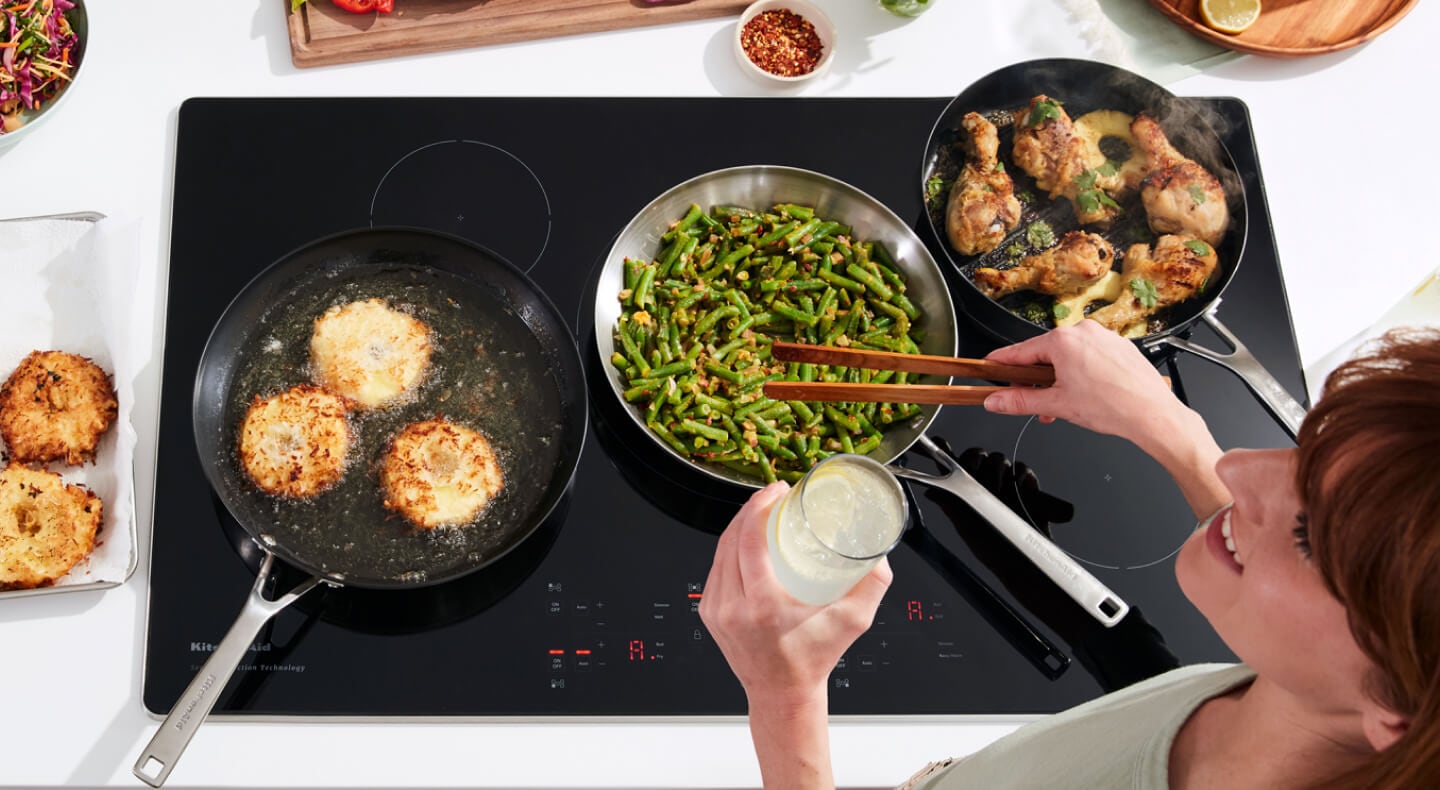 Person cooking chicken, green beans, and biscuits on an induction cooktop Person cooking chicken, green beans, and biscuits on an induction cooktop