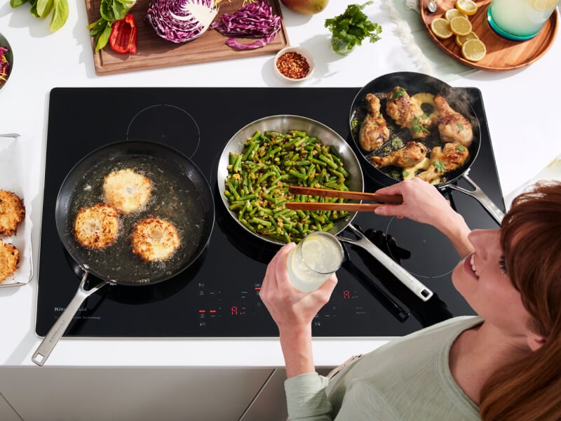 Person cooking chicken, green beans, and biscuits on an induction cooktop Person cooking chicken, green beans, and biscuits on an induction cooktop