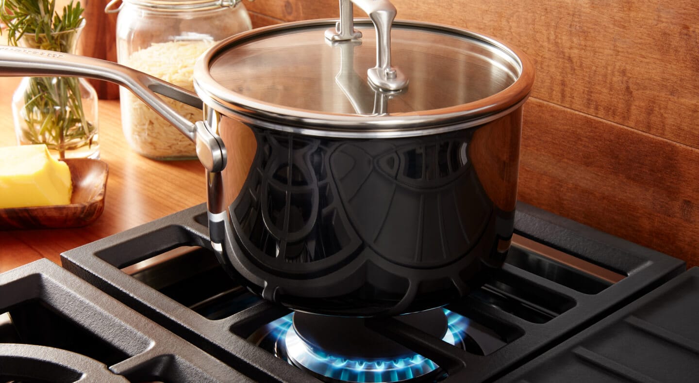 Pot cooking over a gas range against a wooden backsplash. Pot cooking over a gas range against a wooden backsplash.