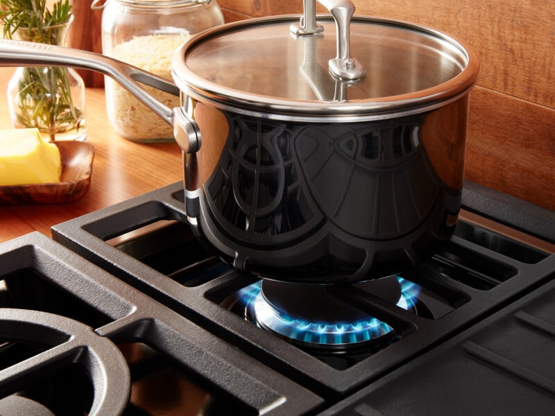 Pot cooking over a gas range against a wooden backsplash. Pot cooking over a gas range against a wooden backsplash.