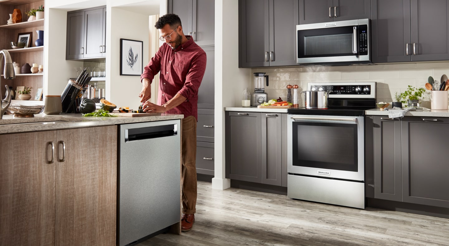 Person chopping veggies in a kitchen with a suite of KitchenAid® appliances Person chopping veggies in a kitchen with a suite of KitchenAid® appliances