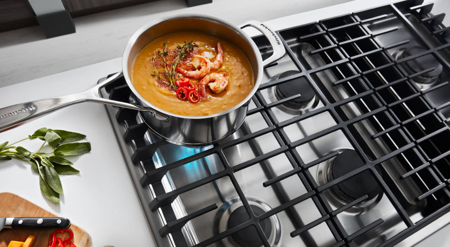 A medium pot sitting on an activated KitchenAid® stovetop burner