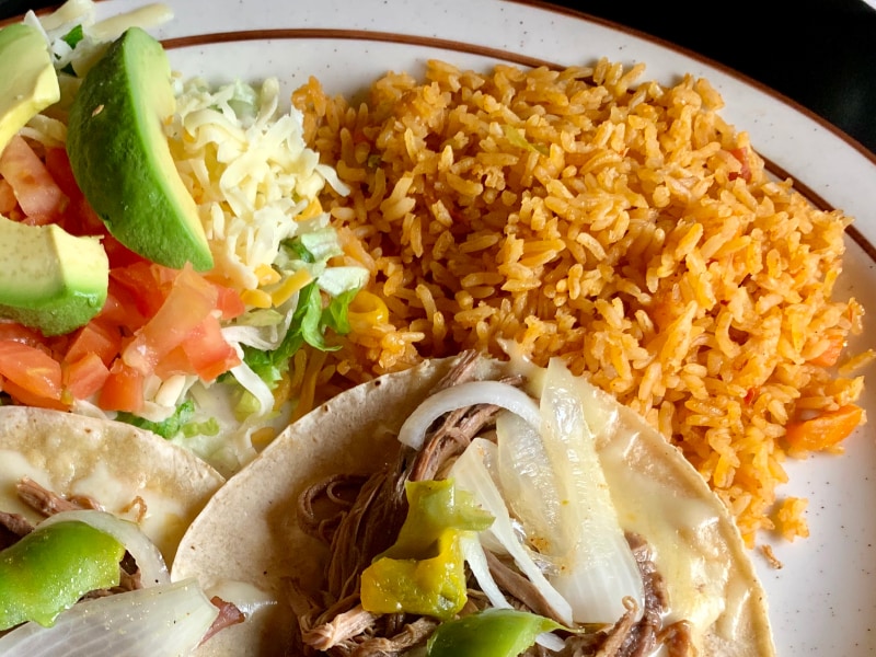 Seasoned rice on a plate with tacos and avocado Seasoned rice on a plate with tacos and avocado