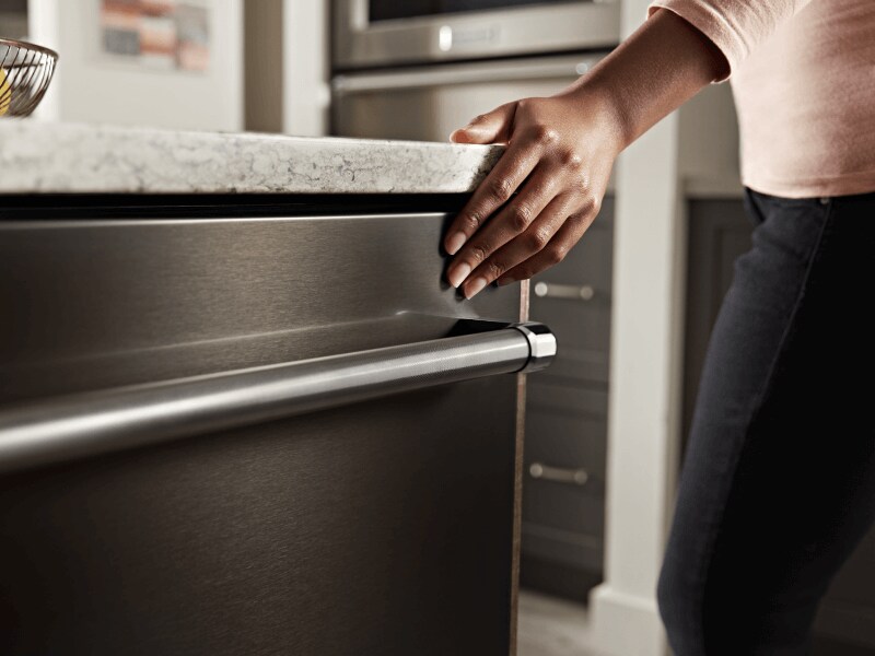 Person closing a KitchenAid® top control dishwasher Person closing a KitchenAid® top control dishwasher
