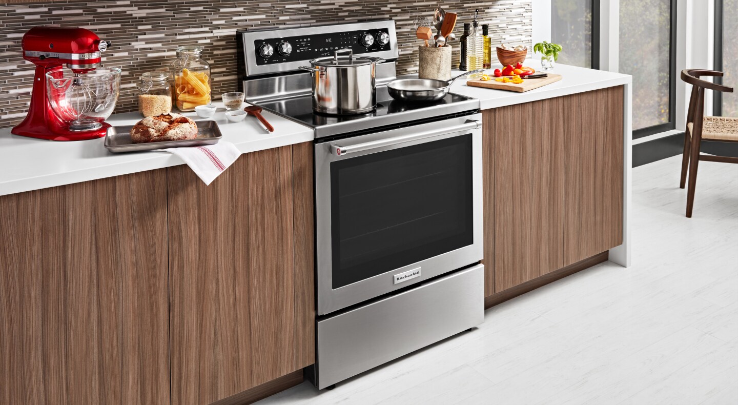 A stainless steel KitchenAid® slide-in range next to prepared dishes A stainless steel KitchenAid® slide-in range next to prepared dishes