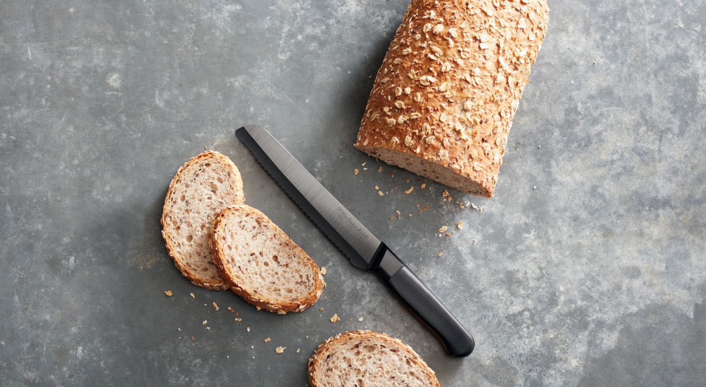 Half sliced loaf of bread on countertop with knife Half sliced loaf of bread on countertop with knife