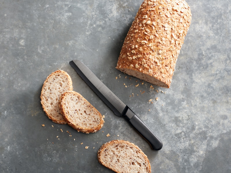 Half sliced loaf of bread on countertop with knife Half sliced loaf of bread on countertop with knife
