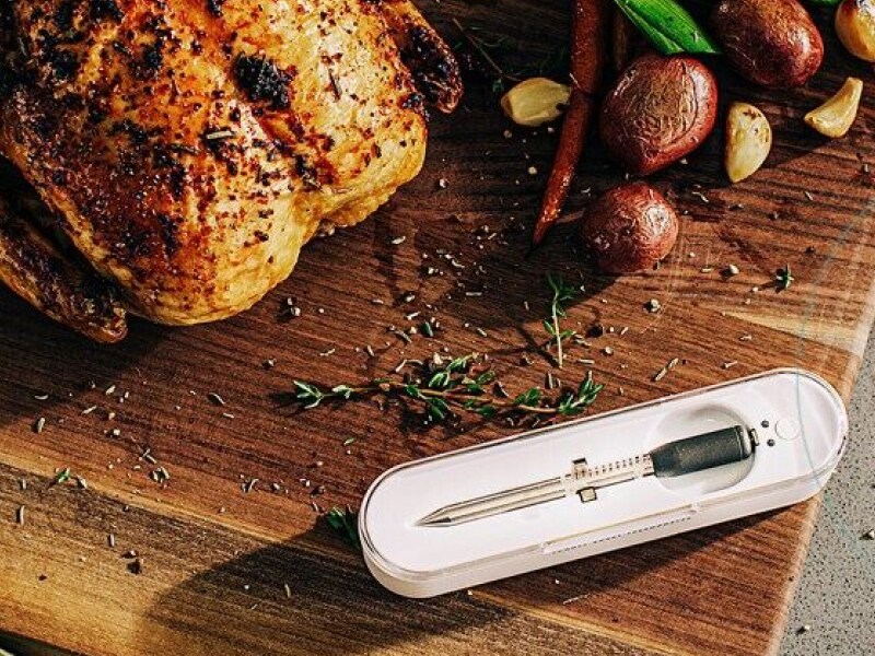 Rotisserie chicken on a cutting board next to a food thermometer and roasted potatoes