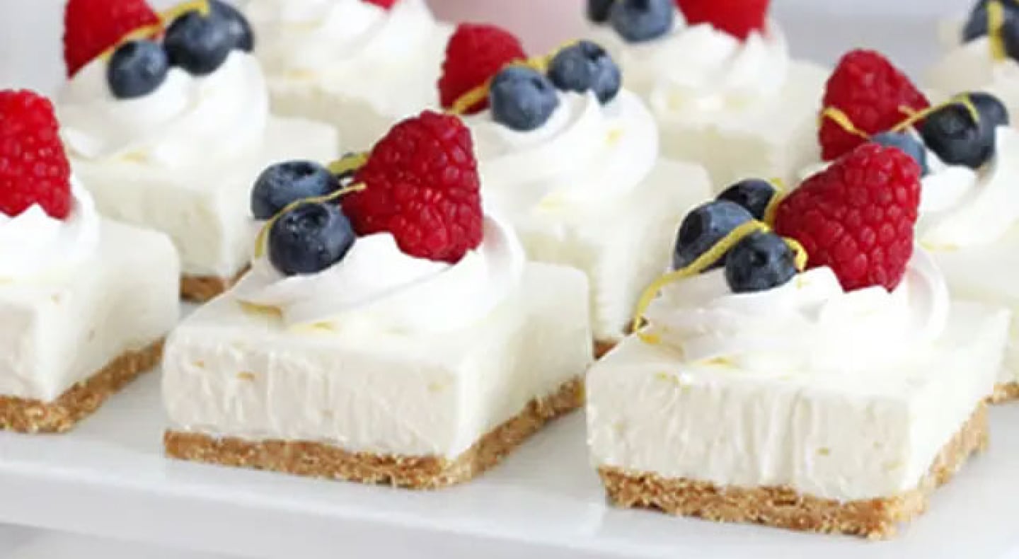 Cheesecake squares topped with whipped cream and fresh fruit Cheesecake squares topped with whipped cream and fresh fruit