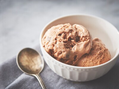 White bowl of chocolate ice cream next to spoon