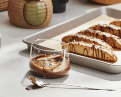 Mocha syrup in a glass cup beside homemade biscotti
