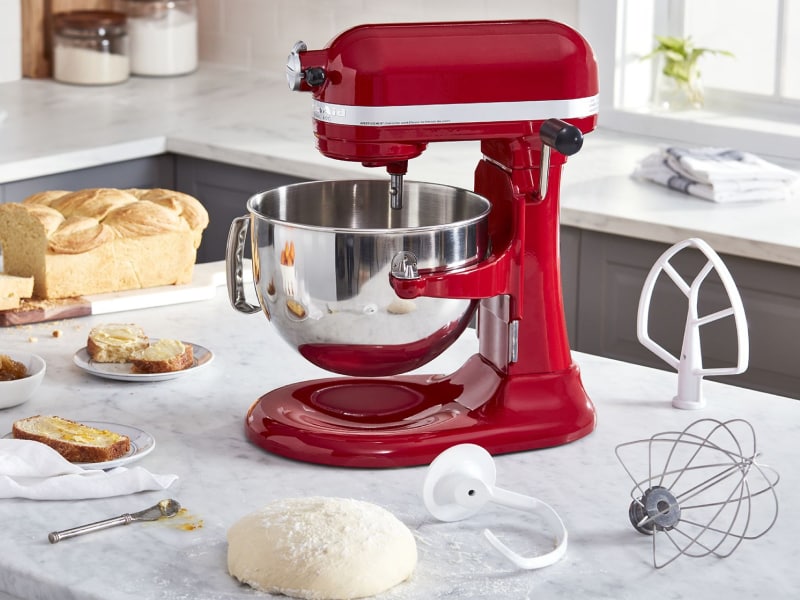 Dough rising on a counter next to a red Kitchenaid® bowl-lift stand mixer and assorted attachments