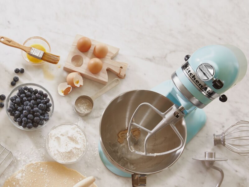 Birds-eye view of light blue stand mixer surrounded by blueberry muffin ingredients Birds-eye view of light blue stand mixer surrounded by blueberry muffin ingredients