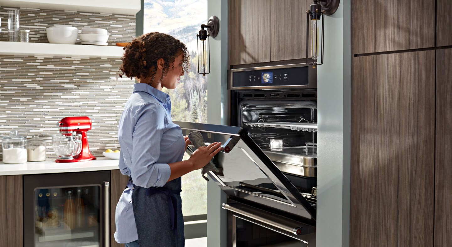 Person closing the door of a wall oven Person closing the door of a wall oven