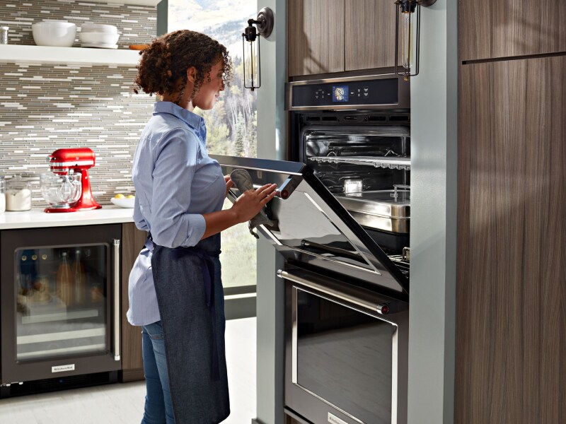 Person closing the door of a wall oven Person closing the door of a wall oven