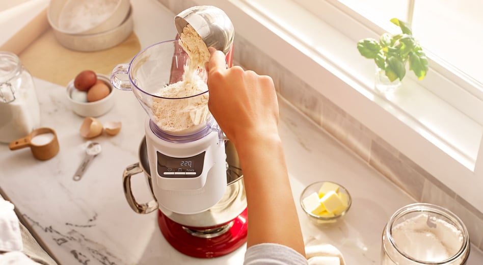 Person pouring flour into a Sifter + Scale Attachment for stand mixer