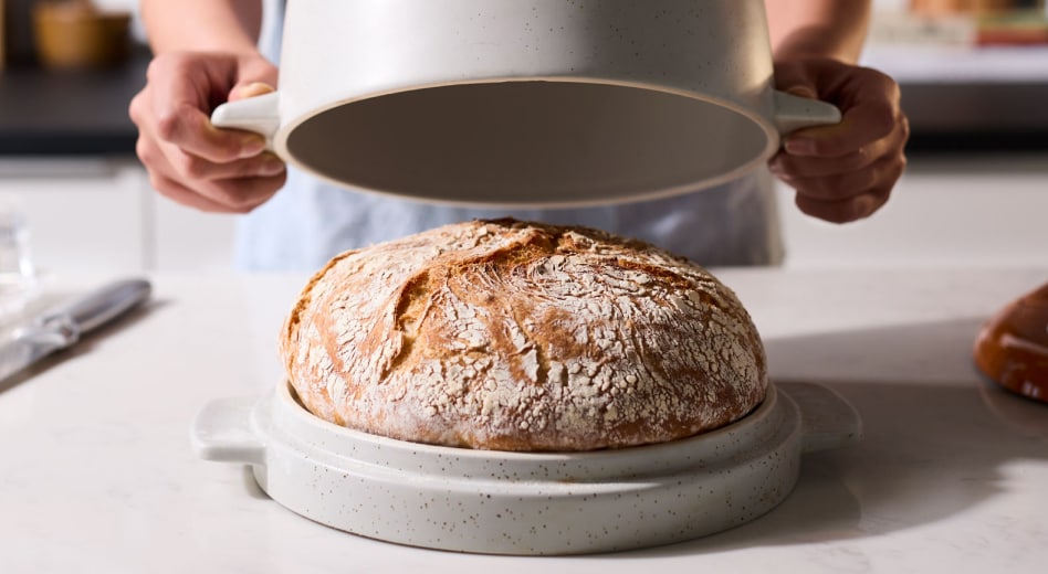 Person lifting the lid off of KitchenAid® Bread Bowl to reveal baked bread
