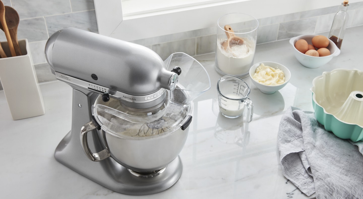 Stainless steel stand mixer next to to cake batter ingredients Stainless steel stand mixer next to to cake batter ingredients