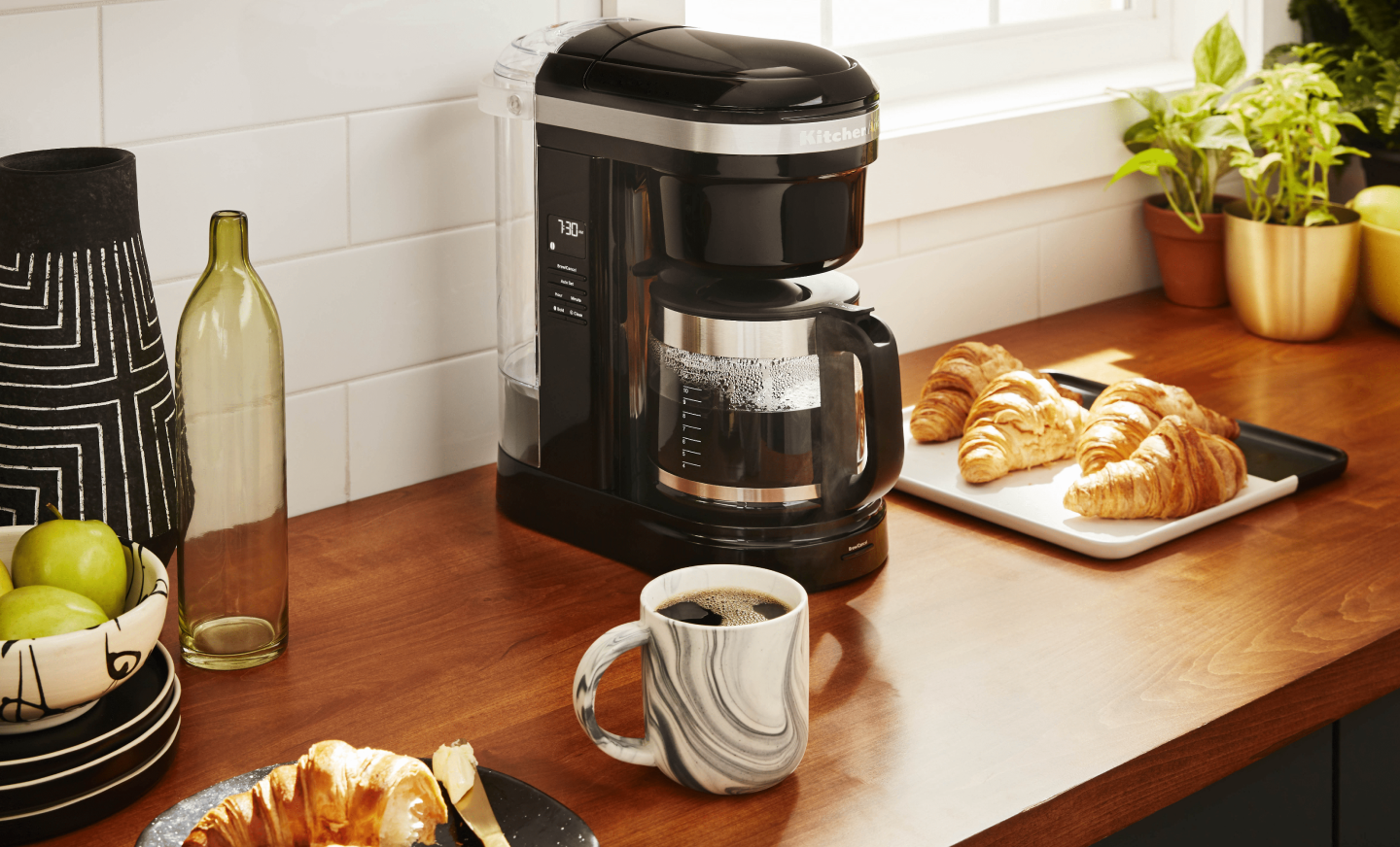 KitchenAid® coffee maker on countertop with croissants and mug of coffee KitchenAid® coffee maker on countertop with croissants and mug of coffee