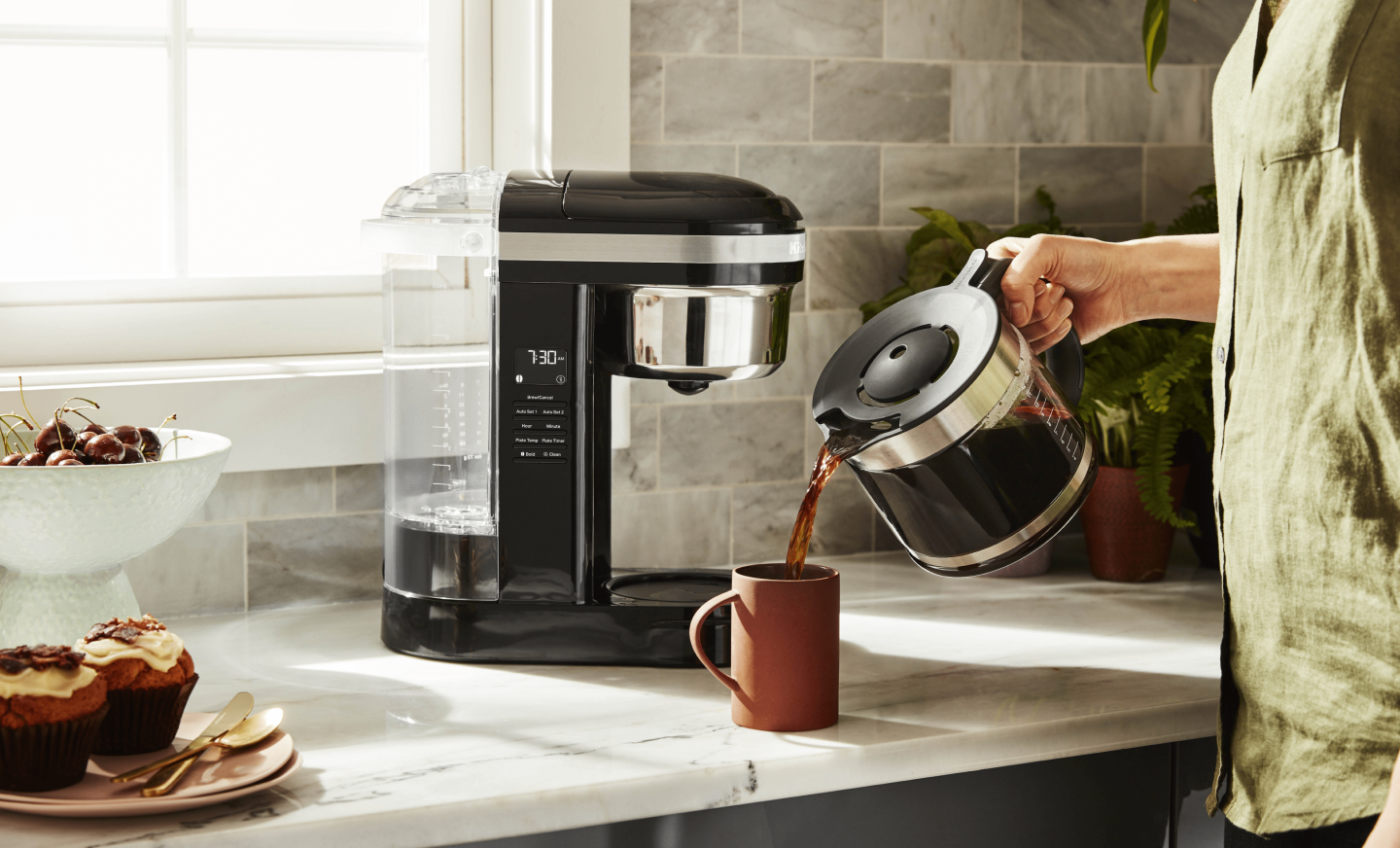 Woman pouring coffee into cup from KitchenAid® coffee maker Woman pouring coffee into cup from KitchenAid® coffee maker