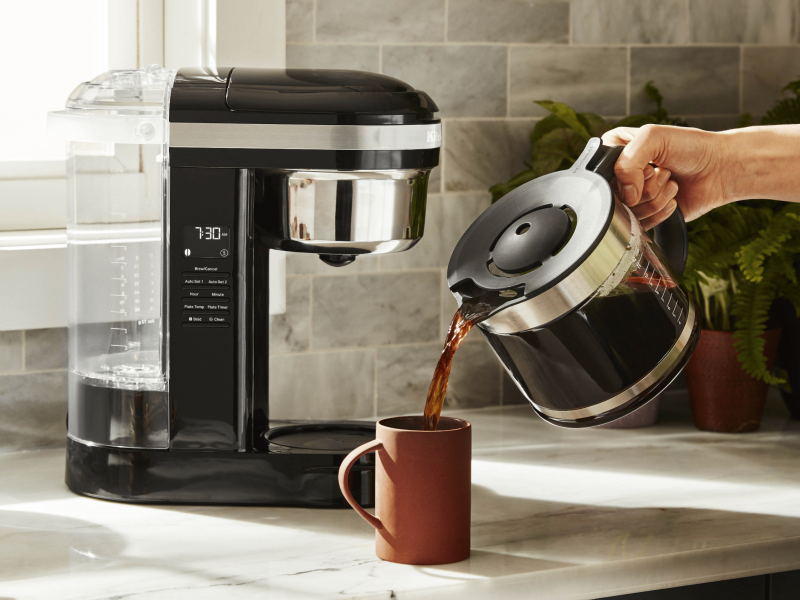 Woman pouring coffee into cup from KitchenAid® coffee maker Woman pouring coffee into cup from KitchenAid® coffee maker