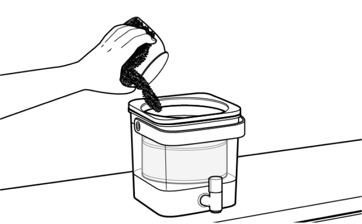 Hand pouring grounds into cold brewer filter