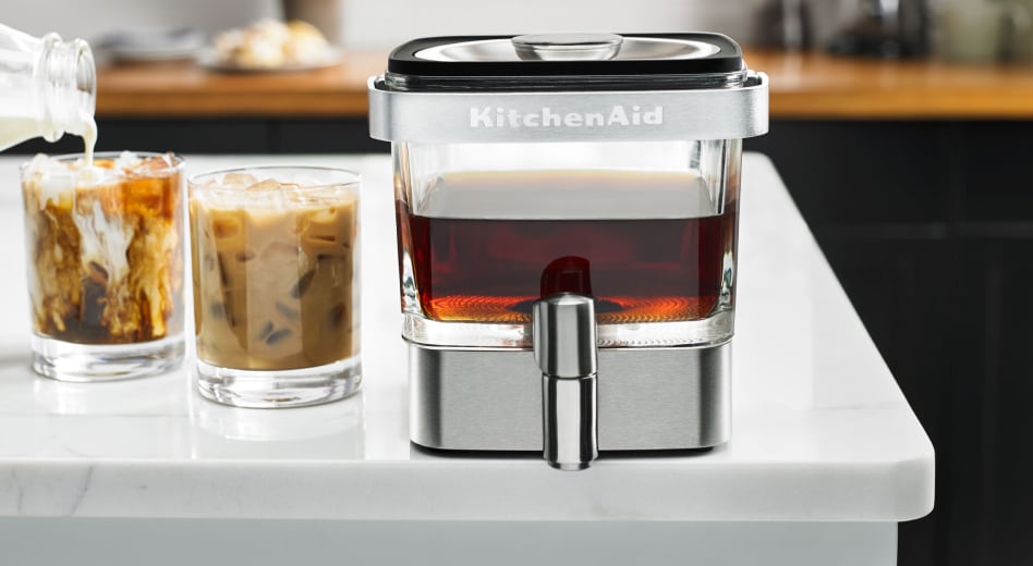 Cold brewer on counter with glasses of cold brew coffee and cream