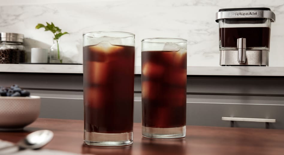 Two tall glasses of iced cold brew coffee on counter Two tall glasses of iced cold brew coffee on counter