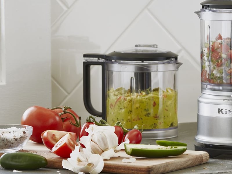 Guacamole and salsa in food processors on counter Guacamole and salsa in food processors on counter