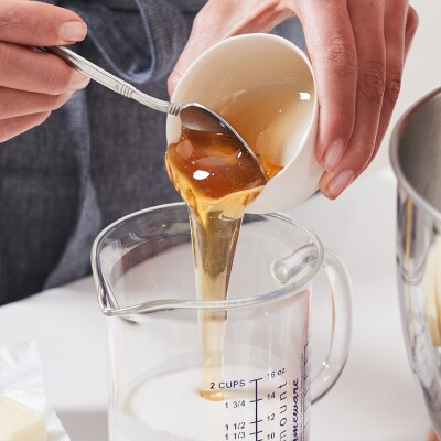 Person adding a liquid into a measuring cup