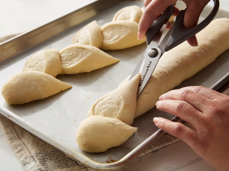 Person cutting dough with scissors