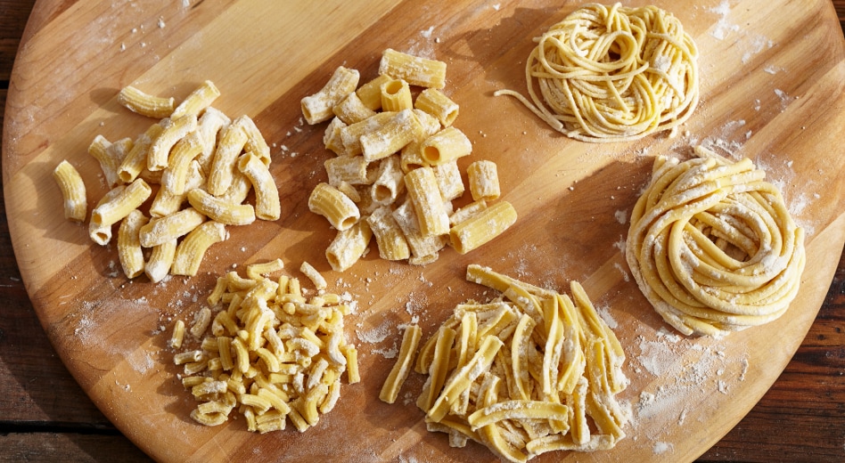Wooden board with nests of fresh pasta in different shapes Wooden board with nests of fresh pasta in different shapes